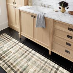 a bathroom with a sink, rug and cabinets in the corner on the floor next to it