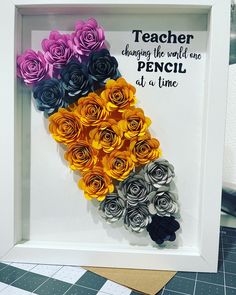 there is a frame with paper flowers in it that says teacher changing the world one pencil at a time