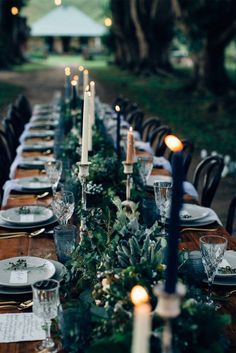 a long table is set with candles, plates and place settings for an elegant dinner