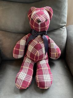 a red teddy bear sitting on top of a gray couch