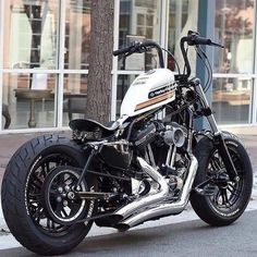 a white and black motorcycle parked on the side of the road next to a tree