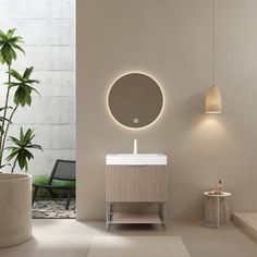 a white sink sitting under a round mirror next to a potted plant in a bathroom