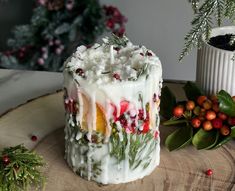 a decorated cake sitting on top of a wooden table next to greenery and berries