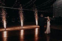 a bride and groom standing in front of fireworks