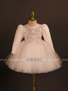 a white dress with sequins and beads on the neckline is displayed in front of a mannequin