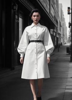 a woman is walking down the street wearing a white coat