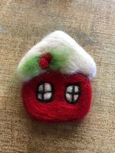 a red and white felt house ornament sitting on top of a wooden table