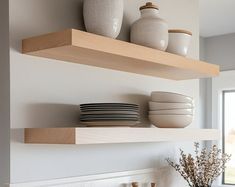 two open shelves with plates and bowls on them in front of a kitchen counter top