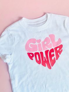 Graphics Tees / Girls & Adult  Front Design: Girl Power Back: Blank  Details:  - Gildan Tshirt - Soft Cotton    (100% Cotton), short sleeve.  - Front Design: Red & Pink Vinyl  - T-shirt colors available:      * Black     * White  * The sizing of the design will be proportional to the size of the t-shirt * Available sizes: * Toddler & Youth  - 2T - 3T - 4T - 5T - 6 - 8 - 10 - 12 * Teen's & Adult  - XSmall  - Small  - Medium  - Large - XLarge  - XXLarge Super comfortable, soft and fashionable. Playful Letter Print T-shirt, Playful Pink T-shirt With Slogan, Cute Pink T-shirt With Text Print, Pink Cotton T-shirt With Heart Graphic, Unisex Pink Playful T-shirt, Girly Tshirt Designs, Trendy Pink Top With Graphic Design, Playful Pink T-shirt With Screen Print, Cute Short Sleeve Tops With Graphic Design