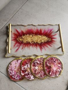 three plates with flowers on them sitting on the floor next to some other items that have been dyed red and gold