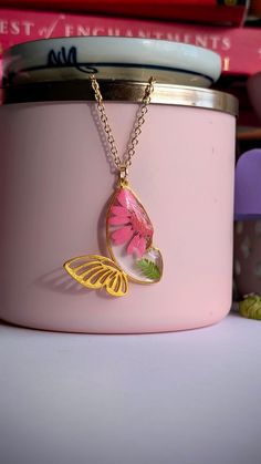 a close up of a pink container with a butterfly necklace on it's neck