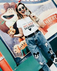 a woman holding a donut in her right hand and wearing mickey mouse t - shirt