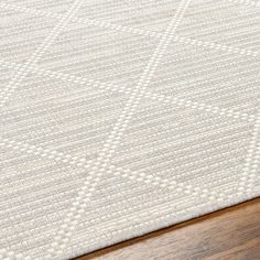 a white rug on top of a wooden floor next to a wood floor with an area rug in the middle