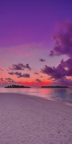 the sun is setting on an empty beach with footprints in the sand and purple clouds