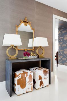 a living room with two stools and a mirror on the wall next to it