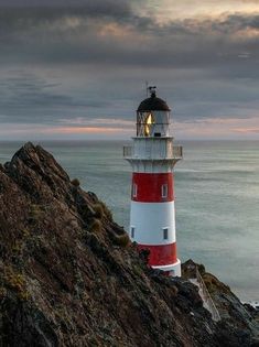 a red and white lighthouse sitting on top of a cliff