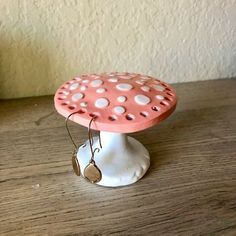 a pink and white ceramic mushroom on a wooden table