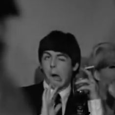 a man in a suit and tie holding a beer bottle while talking on the phone