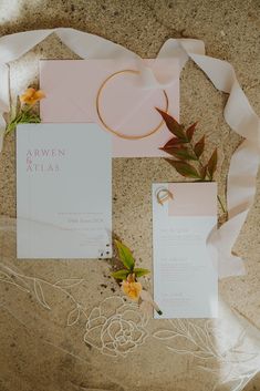 the wedding stationery is laid out on top of the marble floor with ribbon and flowers