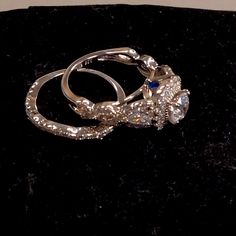 two silver rings sitting on top of a black velvet surface, with one ring attached to the other