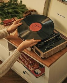 a woman holding an old record player in front of a christmas tree and other decorations