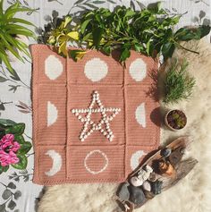 a crocheted rug with a star on it next to some potted plants