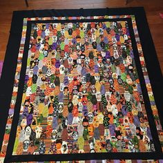 a large quilt is on the floor in front of a wooden table with scissors and other items