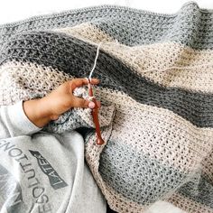 a child is knitting on a blanket with crochet needles and yarn in front of them