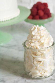 a small jar filled with whipped cream next to raspberries