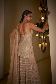 This sharara set features all-over sequin embroidery on a champagne net base. The strappy top is paired with a matching net dupatta.From Seema Gujral's Fiori collection. DELIVERY TIMEPlease allow 8-12 weeks for your outfit to arrive. FABRIC DETAILSNet Professional cleaning only. Grey Kurti Outfit, Champagne Indian Outfit, Seema Gujral Sharara, Glamorous Designer Palazzo Set With Sheer Dupatta, Glamorous Sets With Mirror Work In Chinon, Glamorous Chinon Lehenga For Festive Season, Glamorous Chinon Sets With Mirror Work, Glamorous Gold Sharara With Mirror Work, Glamorous Party Sharara With Mirror Work