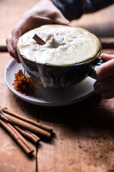 a person holding a cup filled with hot chocolate on top of a white saucer