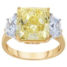 a yellow diamond ring with three white diamonds