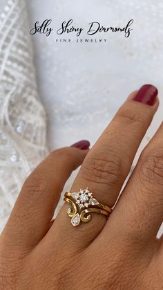 a woman's hand wearing a gold ring with two diamonds on the middle finger