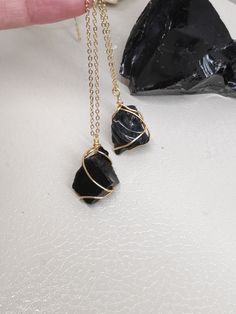 Beautiful Protection Women's Necklace with Raw Black Obsidian Stone wrapped with  Copper wire gold plated, non tarnish.      necklace cord length adjusting approx 35 to 75cm. width 1mm or stainless steel cable chain gold plated in your choice         Stone size approx 2-2,3*1,8-2cm not including wire wrap.   The black obsidian healing properties that are most prominent are its ability to cleanse and ground. It is rooted in the base chakras and has a strong connection to the earth. This makes it Black Crystals Necklace, Spiritual Black Necklace With Raw Stone, Gold Spiritual Obsidian Jewelry, Minimalist Black Wire Wrapped Necklace, Minimalist Black Necklace With Natural Stones, Gold Obsidian Jewelry As A Gift, Black Hand Wrapped Necklace For Gift, Hand Wrapped Black Necklace For Gift, Black Wire Wrapped Pendant Crystal Necklaces