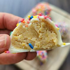 a hand holding a half eaten piece of cake with sprinkles on it