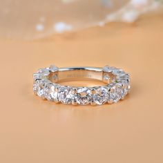 Celebrate your everlasting love story with this elegant band. Stunning as a wedding or anniversary band, it showcases a row of sparkling round stones across the center. With grace and shimmer, this sparkling band is a classic style that complements her sophisticated taste. Carat Weight: 4.125 ctStone Size: 4 mmStone Type: Jeulia® StoneNumber of Stones: 15 Stone Color: Diamond WhiteStone Shape: RoundWeight: 4.38 gWidth: 4.03 mmHeight: 3.92 mmThickness: 2.33 mmMaterial: 925 SilverPlating Color: Si Diamond Eternity Wedding Band, Half Eternity Wedding Band, Unique Wedding Bands, Band Jewelry, Wedding Band Ring, Bridal Bands, Eternity Wedding Band, White Gold Band, Matching Band