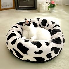 a black and white cat laying in a cow print bed