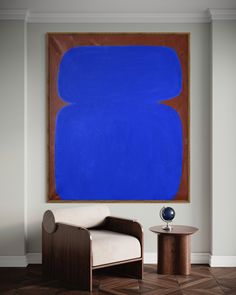 a large blue painting hangs above a chair and table