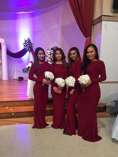 the bridesmaids are all dressed in long sleeved red dresses and bouquets