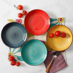 colorful plates and utensils laid out on a white tablecloth with cherries