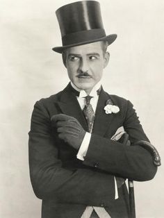 an old black and white photo of a man wearing a top hat with his arms crossed