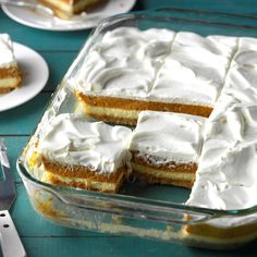 a glass dish filled with cake on top of a blue table next to silverware