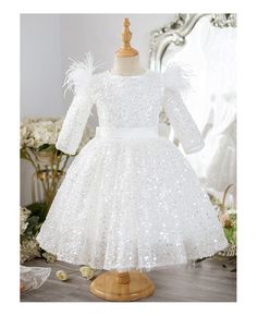 a white dress with sequins and feathers on the shoulders, sitting on a mannequin