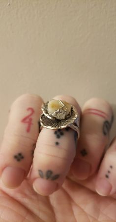 a person's hand holding a ring with tattoos on it