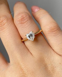 a woman's hand with a diamond ring on top of her finger, showing the center stone