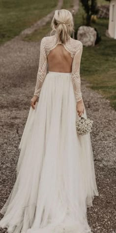 a woman in a wedding dress is walking down the road with her back to the camera