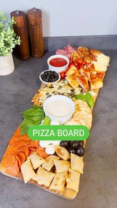 a pizza board sitting on top of a table with olives, cheese and other toppings