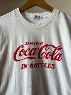 "1950s Coca Cola T-shirt. Has some staining on the front and the back, please refer to photos.  15.5\" Pit to Pit  25.5\" Length All sales final please ask any questions before buying - Thank you!" Vintage Coke Shirt, Vintage Pre-washed Cotton T-shirt, Vintage White T-shirt With Letter Print, Pre-washed Graphic Tee With Crew Neck, Vintage Cotton Pre-washed T-shirt, Vintage Pre-washed Crew Neck T-shirt, Vintage Pre-washed Cotton Tops, Vintage White T-shirt With Screen Print, Vintage Crew Neck T-shirt With Letter Print