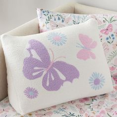 two pillows with butterflies on them sitting next to each other in front of a floral background