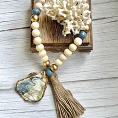 a white and blue beaded necklace with a tassel hanging from it's center